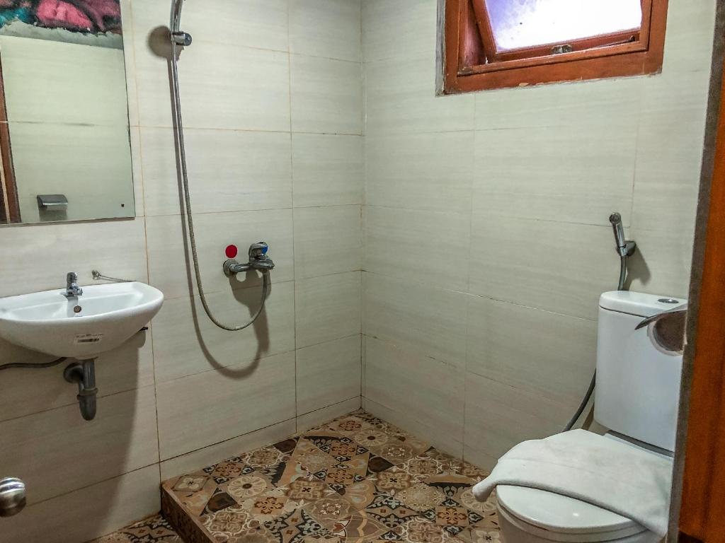 a bathroom with a shower and a toilet and a sink at Arys Garden Hotel Yogyakarta in Yogyakarta