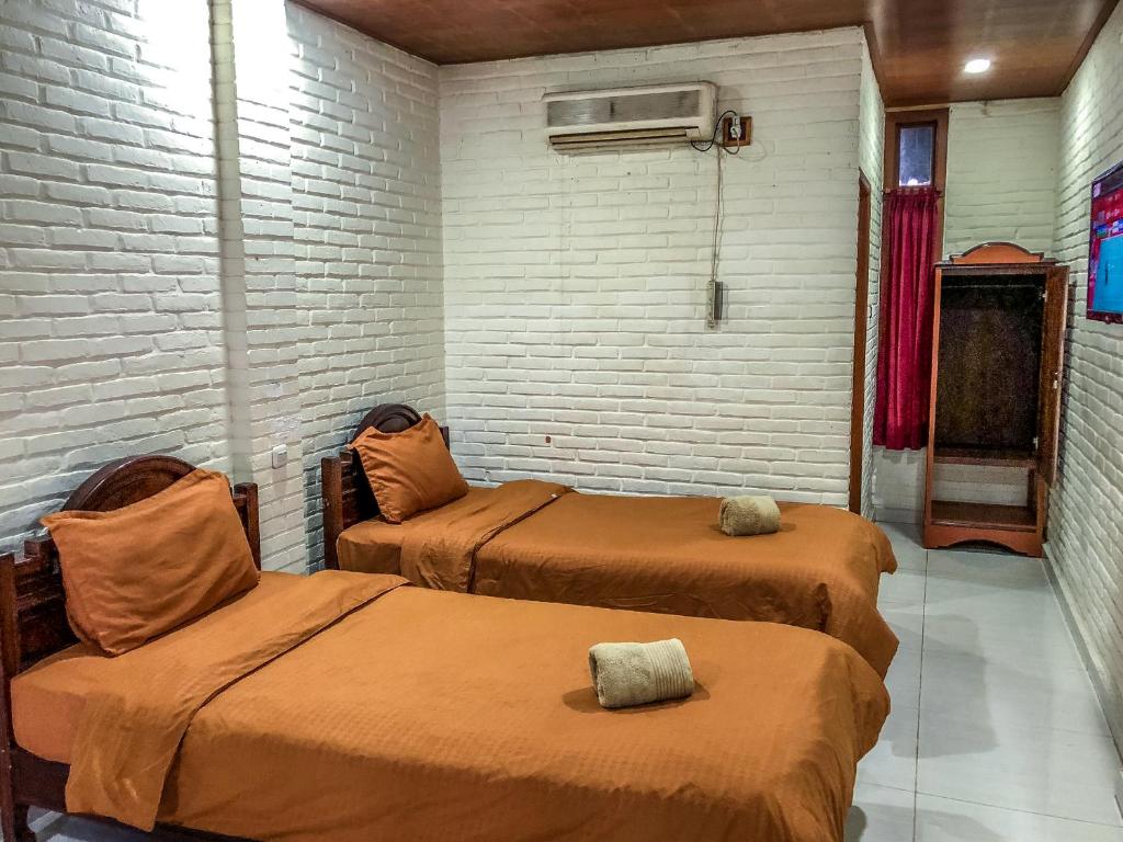 two beds in a room with a brick wall at Arys Garden Hotel Yogyakarta in Yogyakarta