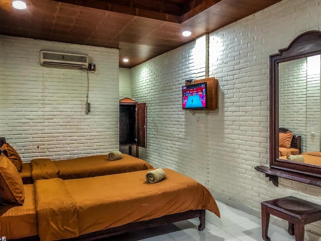 a bedroom with a bed and a tv on a brick wall at Arys Garden Hotel Yogyakarta in Yogyakarta