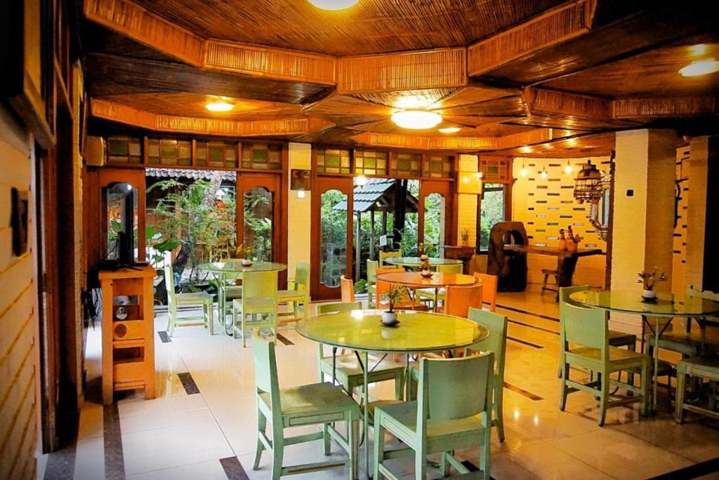 a restaurant with tables and chairs in a room at Arys Garden Hotel Yogyakarta in Yogyakarta