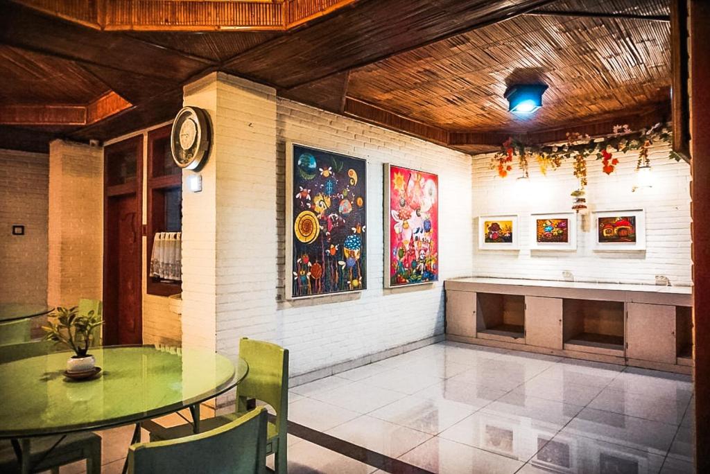 a dining room with a table and a clock on the wall at Arys Garden Hotel Yogyakarta in Yogyakarta