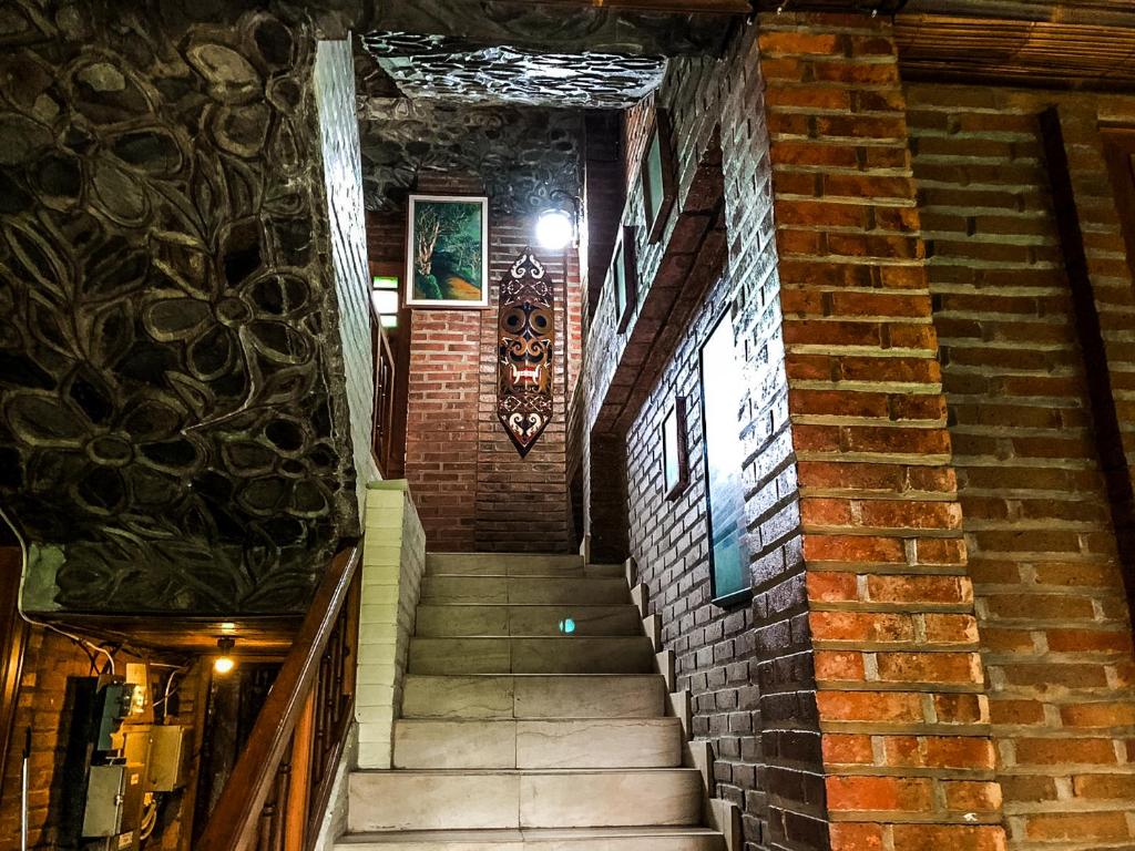 a staircase in a building with a brick wall at Arys Garden Hotel Yogyakarta in Yogyakarta