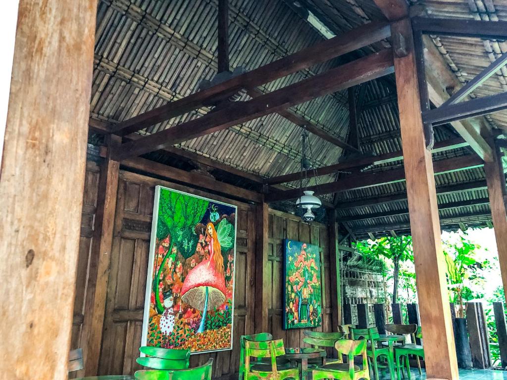 a room with green chairs and paintings on the wall at Arys Garden Hotel Yogyakarta in Yogyakarta