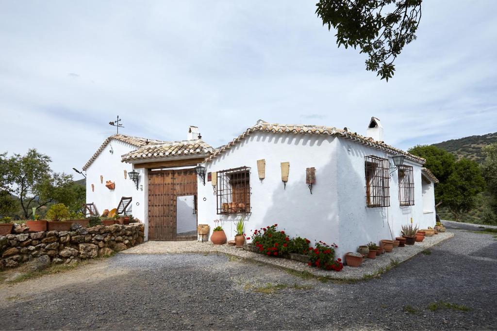 ein weißes Haus mit einer Steinmauer in der Unterkunft Cortijo Rural Majolero 1 in Castillo de Locubín