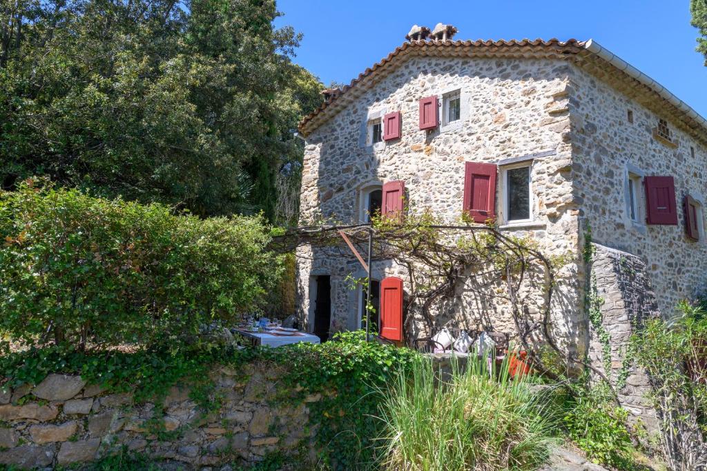 ein altes Steinhaus mit roten Türen und Fenstern in der Unterkunft Le Sivelou - Gîte 9 personnes in Saint-Félix-de-Pallières