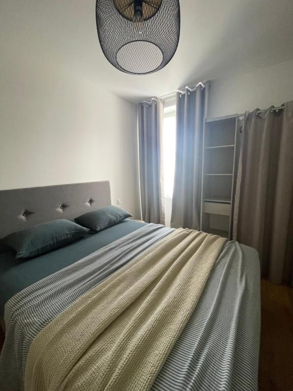 a bedroom with a bed with blue pillows and a lamp at Appartement F3 Corte, centre ville in Corte