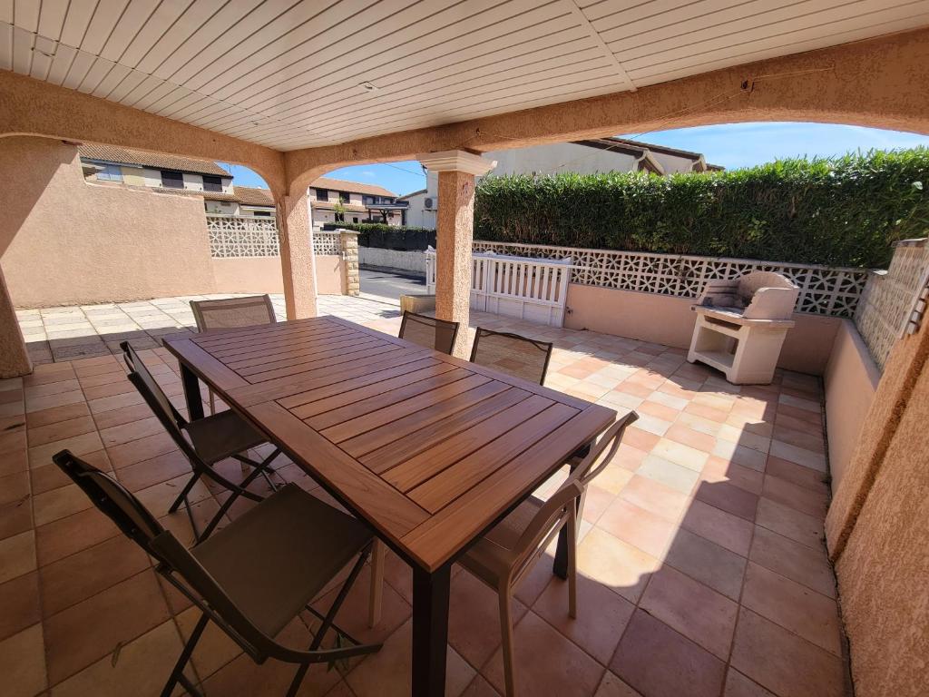 une table et des chaises en bois sur une terrasse dans l'établissement Domaine de vacances à 600m de la plage villa climatisée 3 chambres 7 couchages terrasse WIFI animations et piscines en supplément LRPDSD7, à Portiragnes