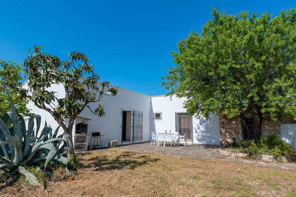 una casa blanca con una mesa y un árbol en Trullo Giovanni, en Ceglie Messapica