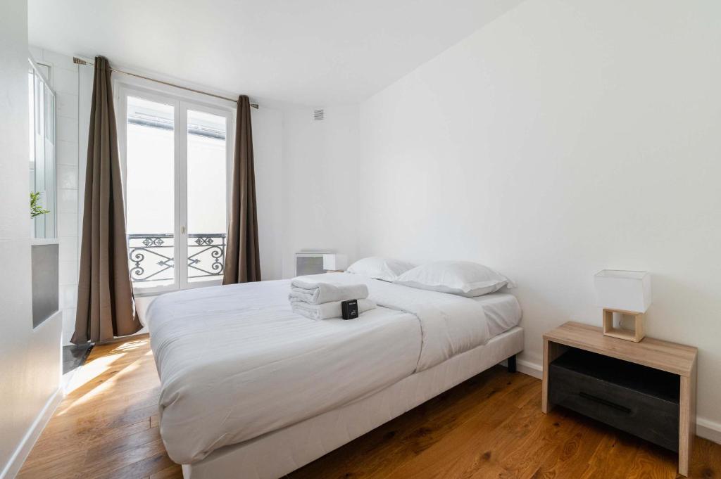 une chambre blanche avec un lit et une fenêtre dans l'établissement 2 pieces cosy hopital bichat - paris 18 - 2P, à Paris