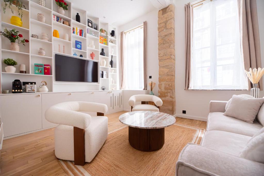 Il comprend un salon doté d'un mobilier blanc et d'une télévision à écran plat. dans l'établissement CIA - Chic Flat in Marais with AC, à Paris