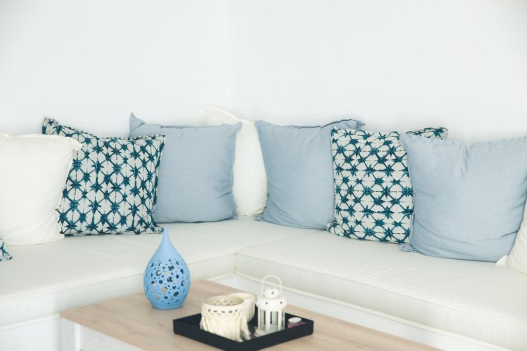 a white couch with blue pillows and a table at Jemphasis-New Apartments Mykonos in Agios Ioannis Mykonos