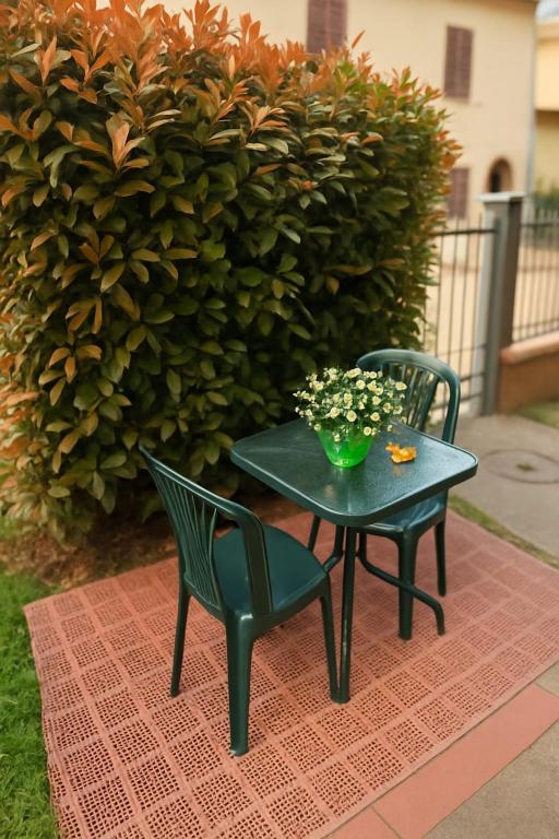 two chairs and a table with a vase of flowers at Appartamento Mary Monteriggioni in Monteriggioni