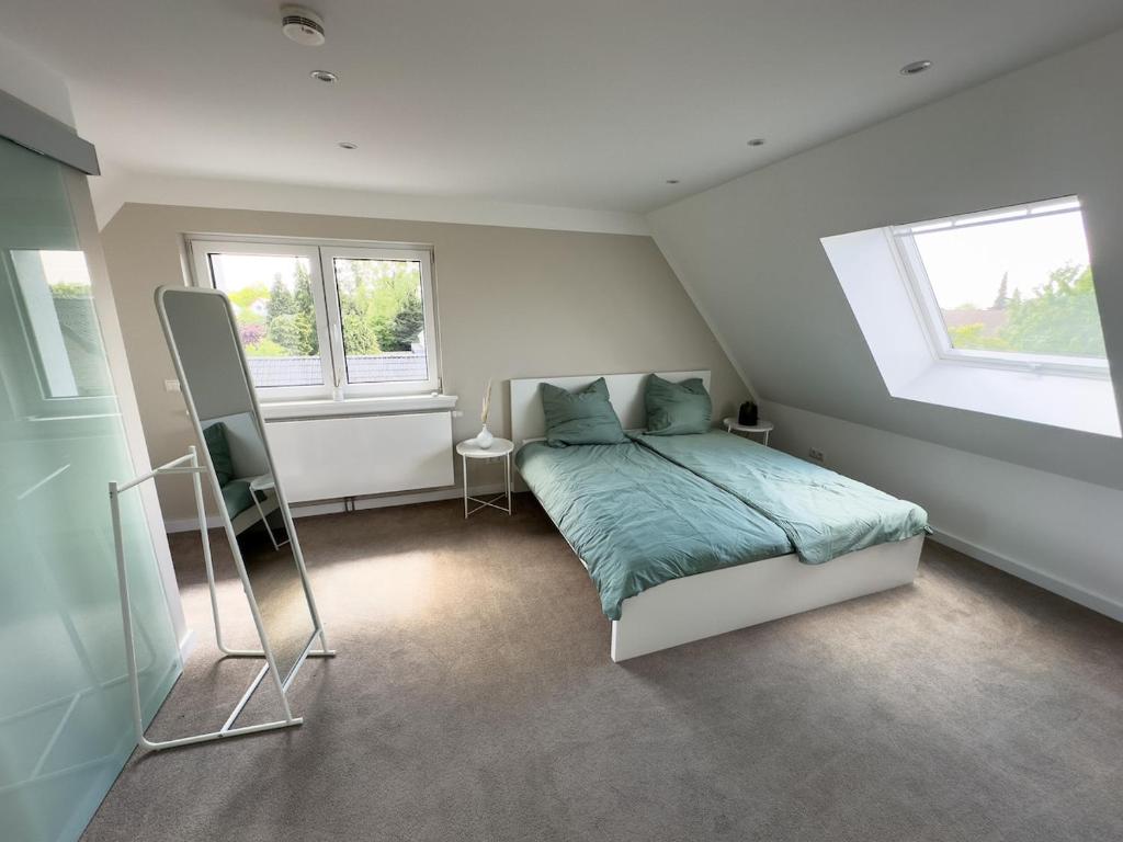 a bedroom with a bed and two windows at Stilvolle Dachgeschosswohnung am Teutoburger Wald in Steinhagen
