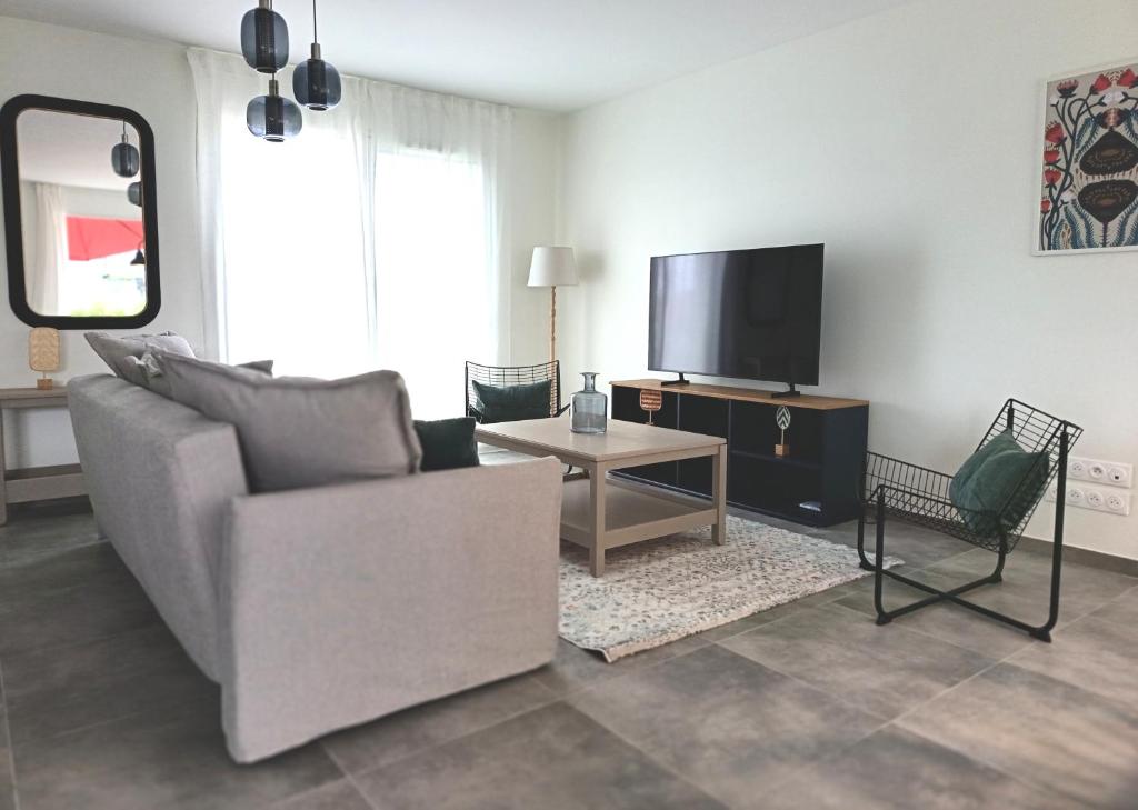 a living room with a couch and a tv at L'Orge - Maison Design, 3 chambres, jardin et garage privatif in Vic-le-Comte