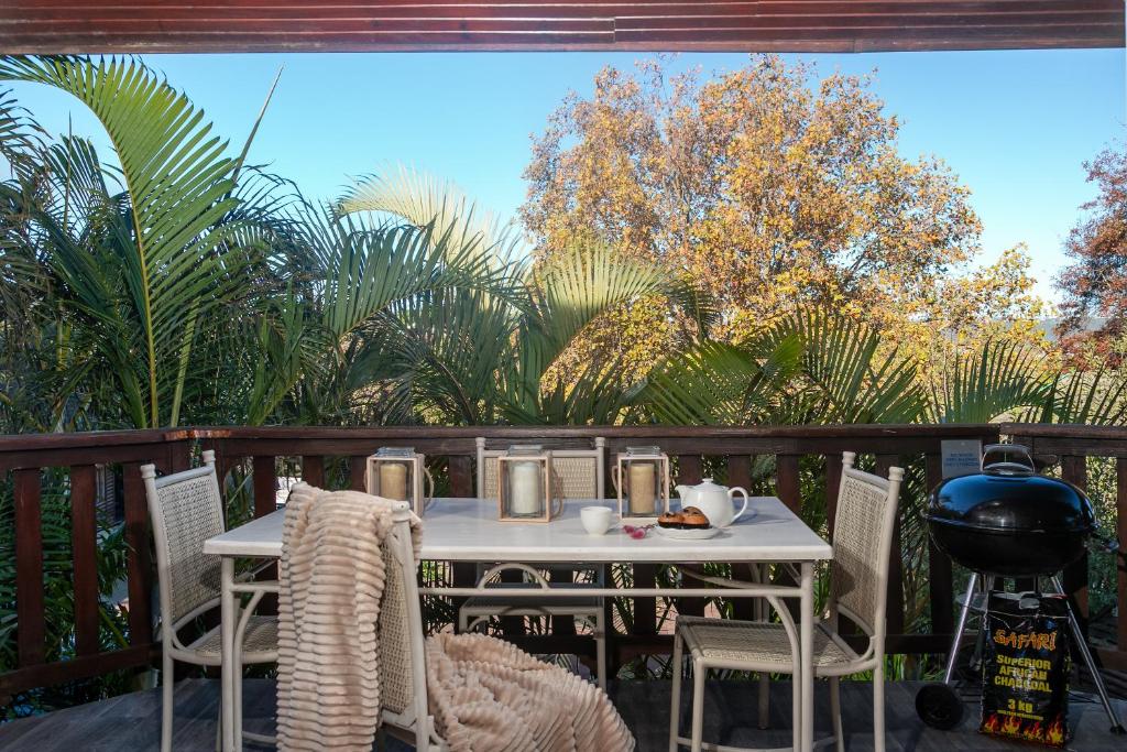 una mesa blanca y sillas en un patio con árboles en Knysna - Sunrise Chalet, en Knysna