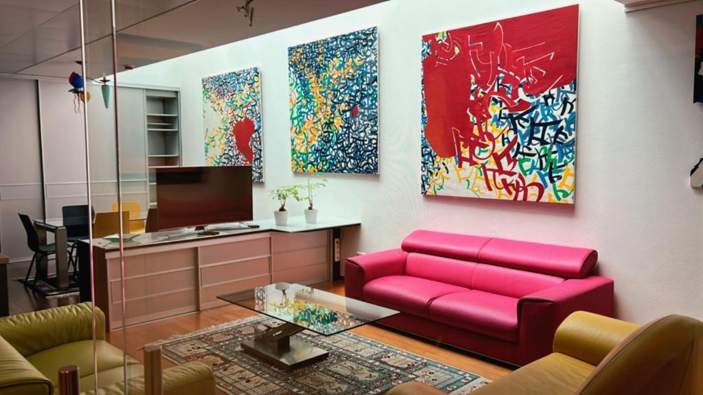 a living room with a red couch and paintings on the wall at Domus Hotel in Luxembourg
