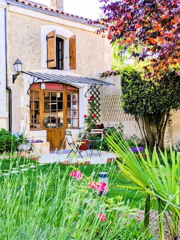 une maison avec une cour fleurie devant elle dans l'établissement Maison Chinsa, à Saint-Angeau