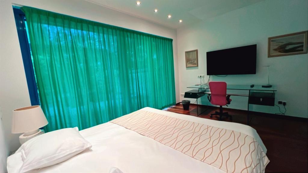 a bedroom with a bed and a television and a chair at Domus Hotel in Luxembourg