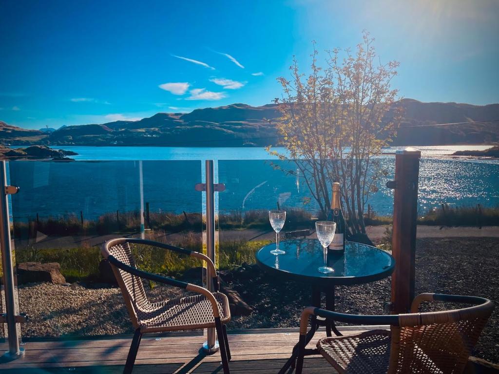 a table and chairs on a deck with a view of the water at Luxury Pod and Sauna with Fantastic Sea Views in Oban