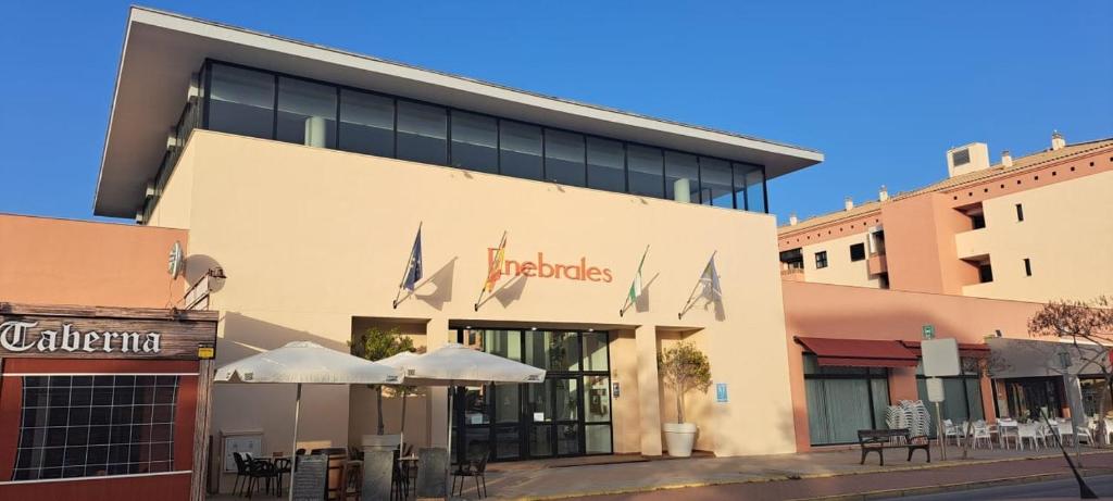 a building with tables and umbrellas in front of it at Enebrales 304 in Punta Umbría