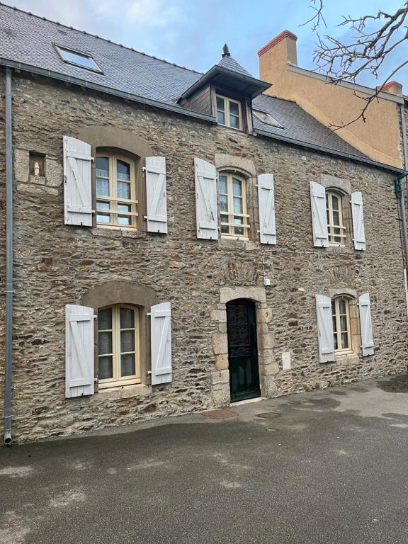 un vieux bâtiment en briques avec des fenêtres blanches à volets dans l'établissement Sarzeau, à Sarzeau
