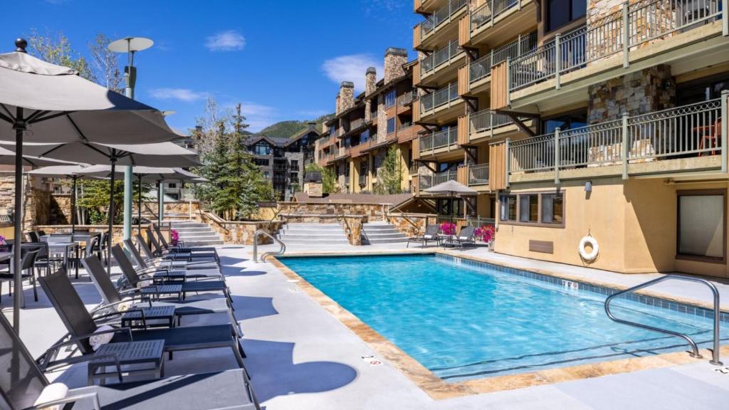 una piscina con sillas y sombrillas en un hotel en Vail - Lionshead Condominiums 2 Bedroom Condo, en Vail