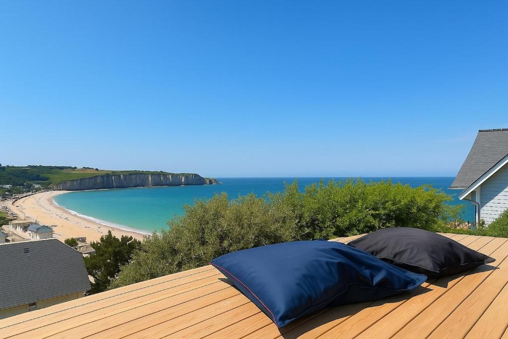 un oreiller bleu posé sur une terrasse en bois avec une plage dans l'établissement Villa with panoramic sea view, à Fécamp