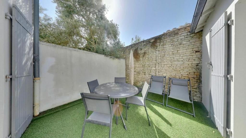 un patio avec une table et des chaises et un mur de briques dans l'établissement 180 La Blanche Courtyard apartment with parking, à Saint-Martin-de-Ré