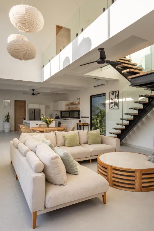 a living room with white furniture and a staircase at Spacious 3 bedroom villa - Walk to the beach in Uluwatu