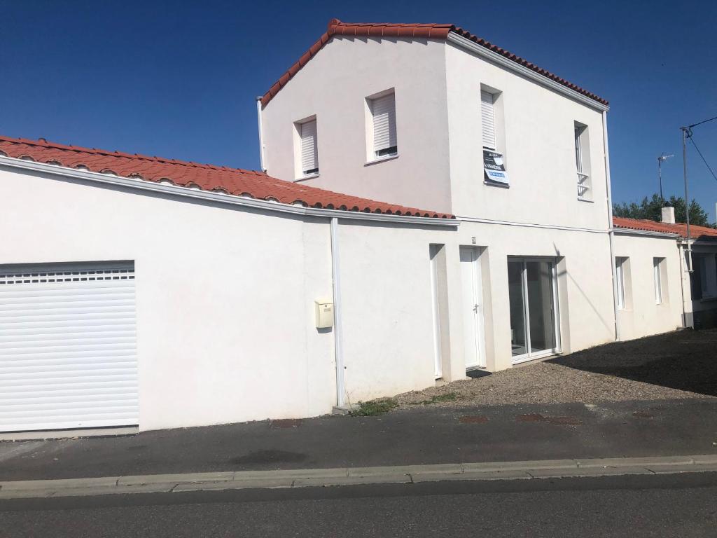 un bâtiment blanc avec un toit rouge dans l'établissement au coeur de la chaume, à Les Sables-dʼOlonne