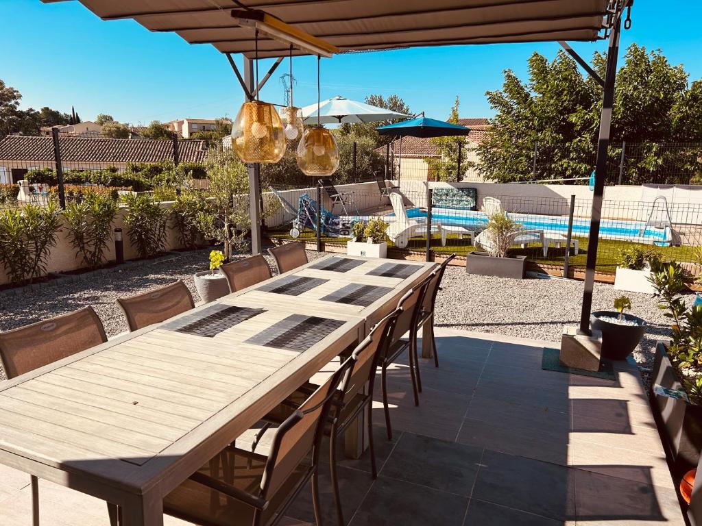 une grande table et des chaises en bois sur la terrasse dans l'établissement Alicante, à Causses-et-Veyran