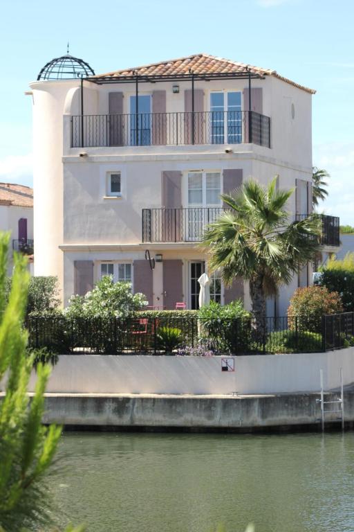 une maison blanche à côté d'une nappe d'eau dans l'établissement La Batelière, entre mer, Camargue et Canaux, à Aigues-Mortes