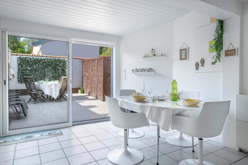 une salle à manger blanche avec une table et des chaises blanches dans l'établissement Vue mer, plage à 50m, Maison pour 4, à La Plaine-sur-Mer