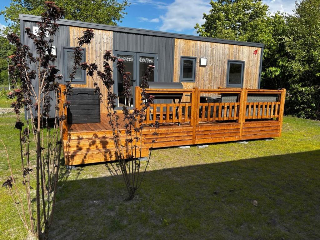 a tiny house with a large deck in a yard at Maison la Rivière in Gasselte