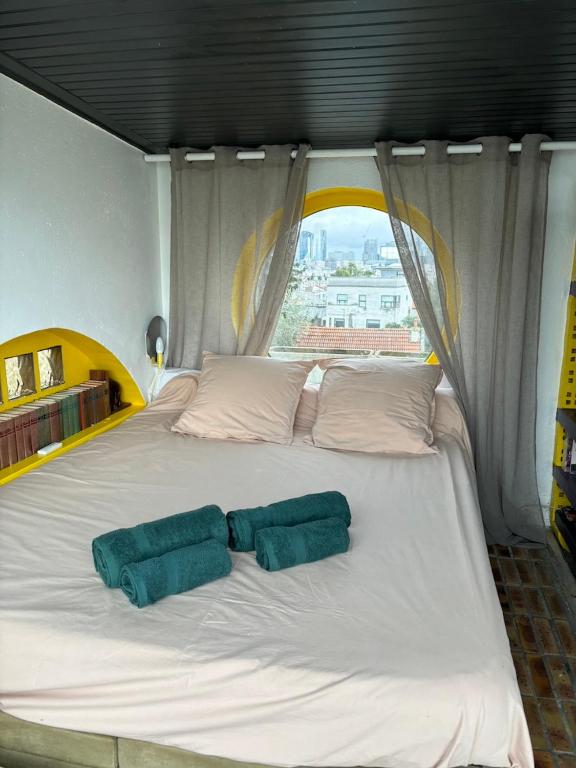 a large white bed with two green pillows on it at Grand studio vue magique sur Paris in Suresnes