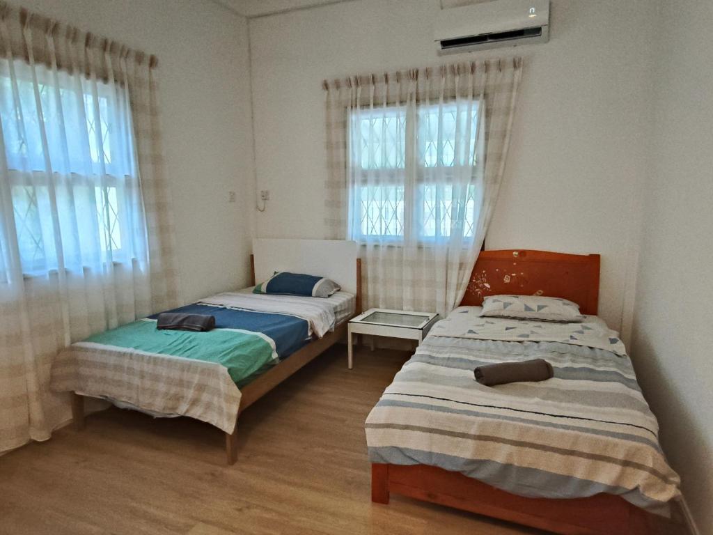 two beds in a room with two windows at Vi Sweet Home- Luak in Gua Sai