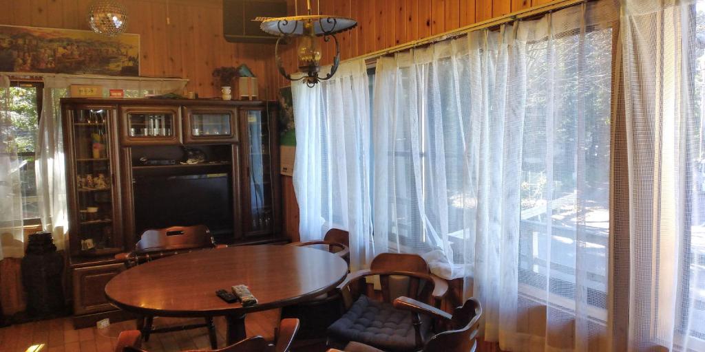 a dining room with a table and a large window at Minpaku Sarai Nikkoya in Okkia