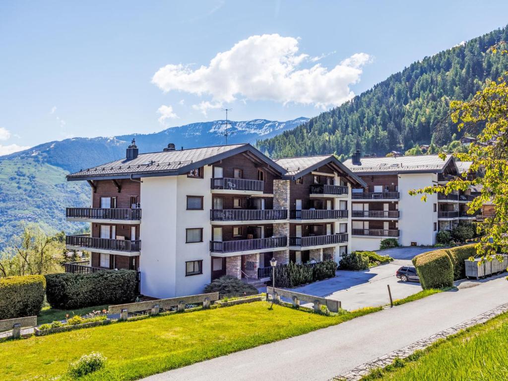 an apartment building with mountains in the background at Apartment Arnica 16 by Interhome in Nendaz