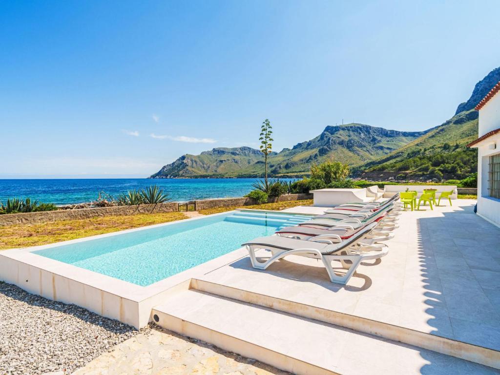 a villa with a swimming pool with chairs and the ocean at Holiday Home Xoroi by Interhome in Colonia de Sant Pere