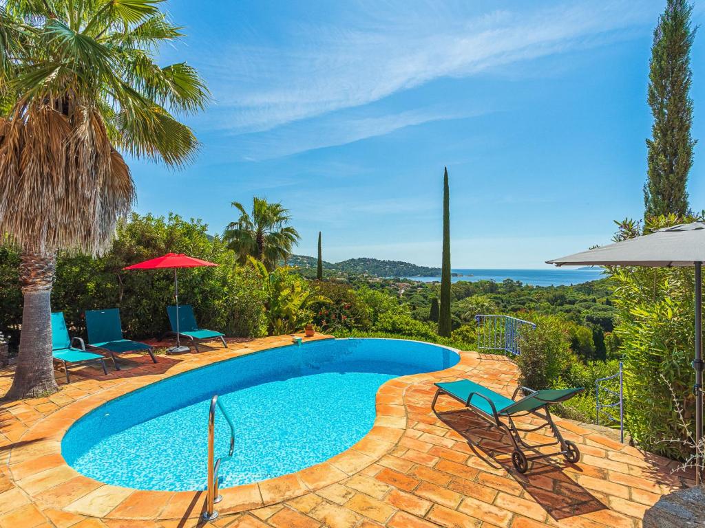 basen z leżakami i parasolami na patio w obiekcie Villa Villa Etoile Filante by Interhome w mieście Le Lavandou