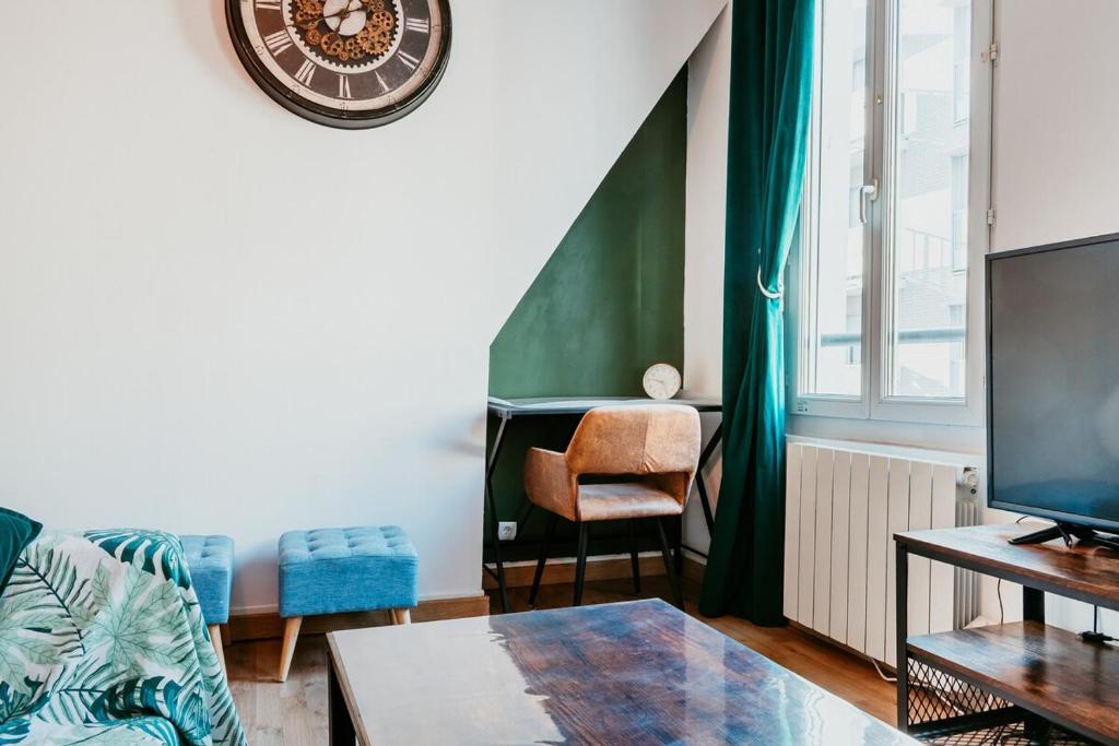 un salon avec un canapé et une horloge au mur dans l'établissement l'Amiral, au Havre