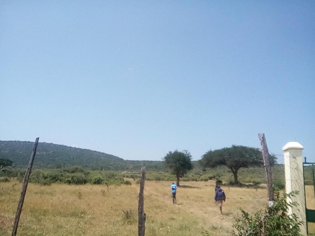 due persone che camminano in un campo dietro una recinzione di Miliki Maasai Mara a Maasai Mara National Reserve