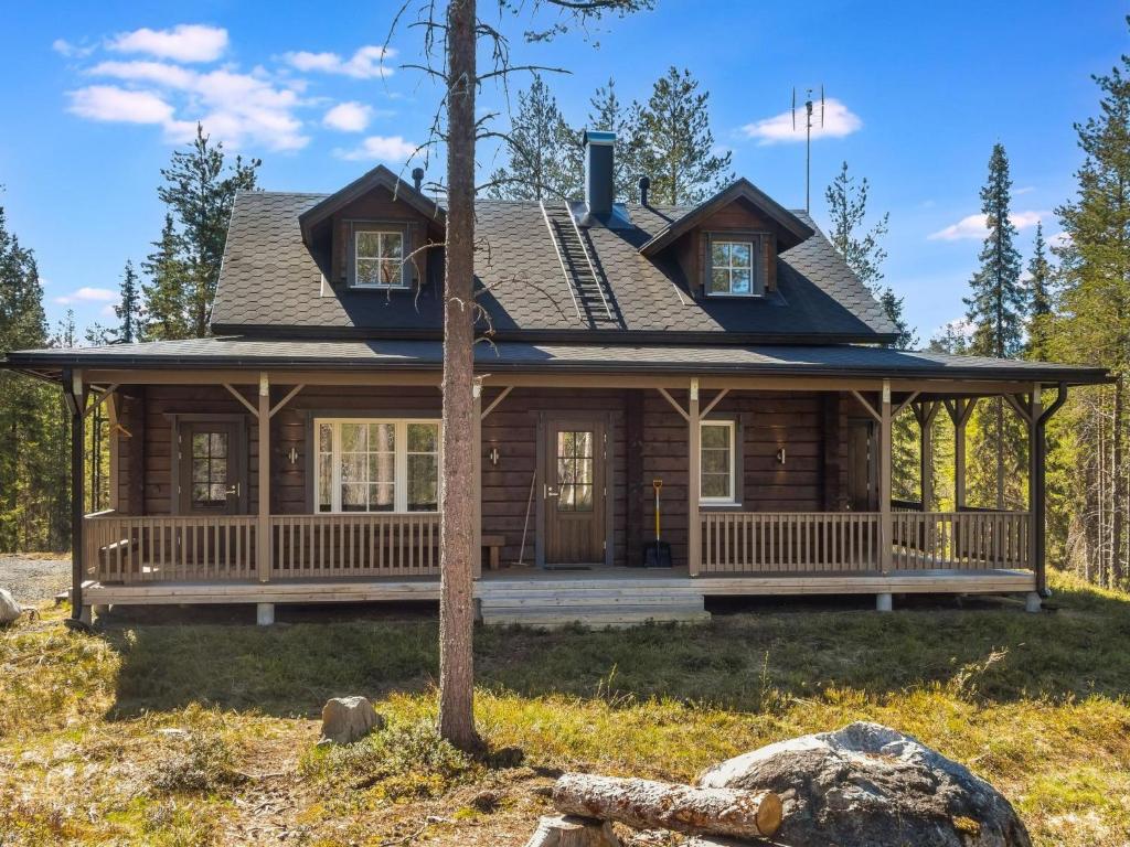 ein Blockhaus mit einer umlaufenden Veranda und einem Haus in der Unterkunft Holiday Home Kiehtäjän kuohu by Interhome in Käylä