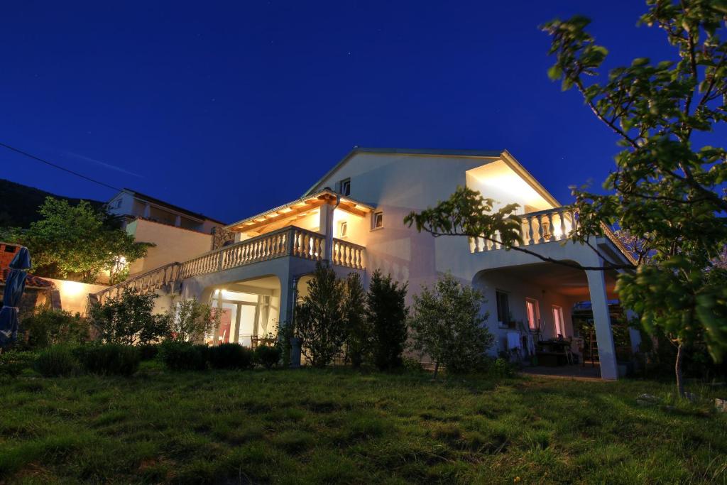 a large white house with a balcony at night at Apartments Tomas in Senj