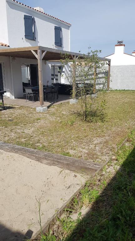 a house with a porch and a yard with a house at VIlla Elise, lumineuse et proche plage in LʼÉpine