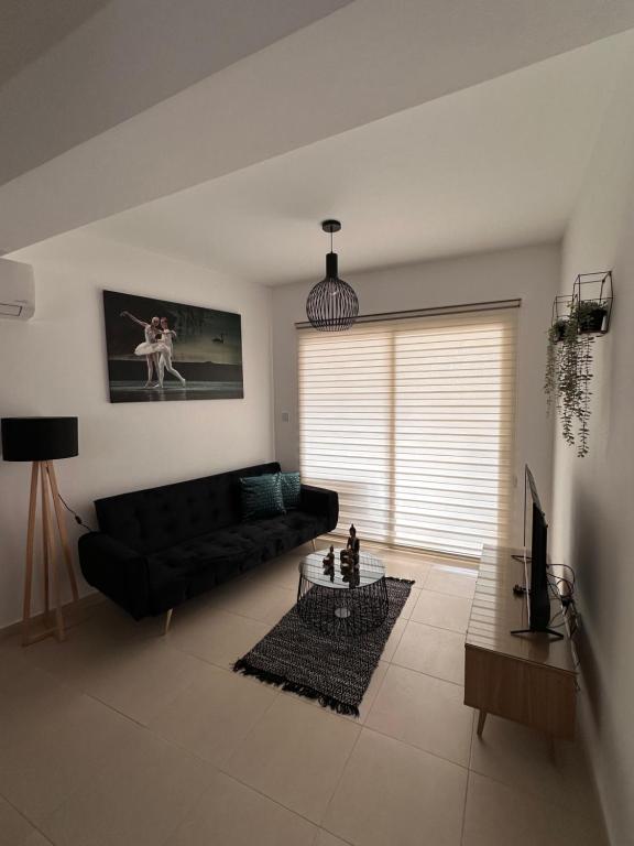 Una sala de estar con un sofá negro y una mesa. en Lucy's holidays apartment, en Peyia