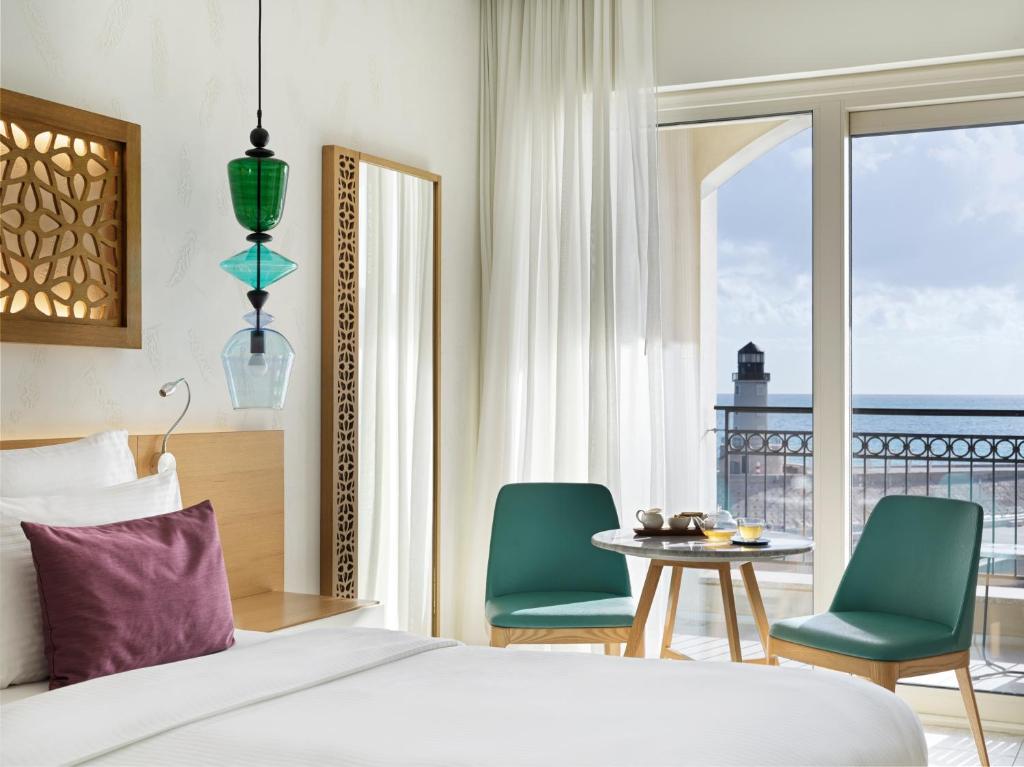 a bedroom with a bed and two chairs and a table at The Chedi Luštica Bay in Tivat
