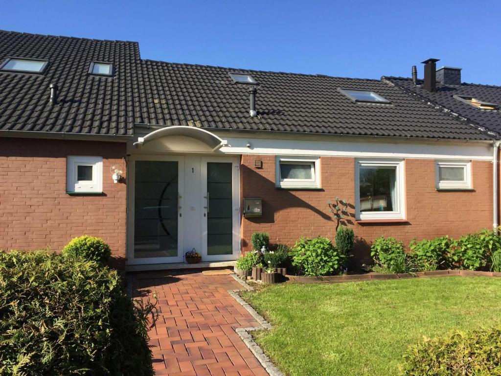 een stenen huis met een groene deur en een tuin bij Ferienwohnung Koriath, 15107 in Leer