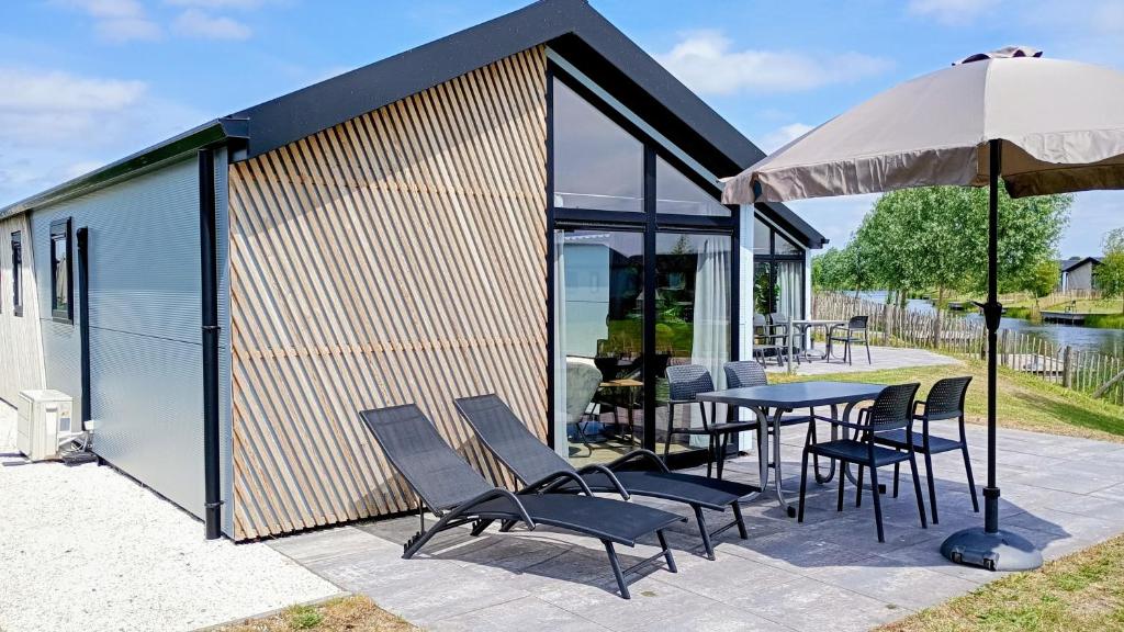 un patio con tavolo, sedie e ombrellone di De IJssel Eilanden Chalet Casa Kampen mit Zaun Nr 548 a Kampen