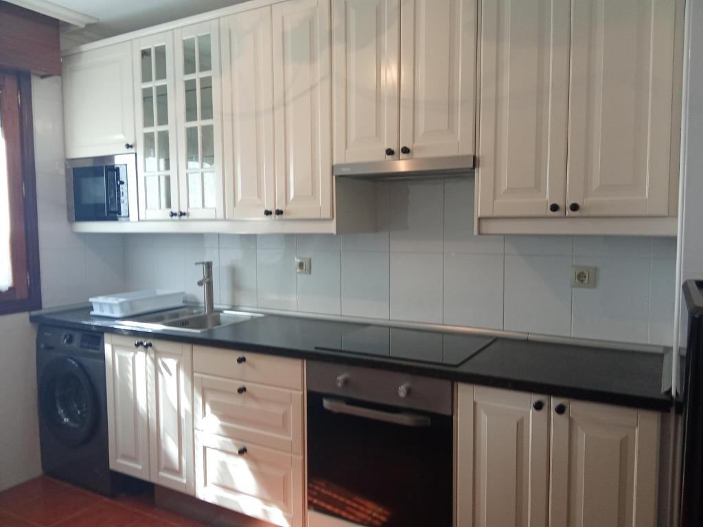 a kitchen with white cabinets and a black counter top at FUENTETRIGO III Medina de Pomar in Medina de Pomar